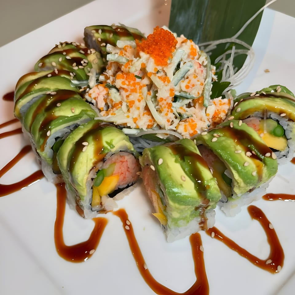 Sushi Guys' avocado-topped sushi rolls with eel sauce and sesame seeds, served with a side salad.