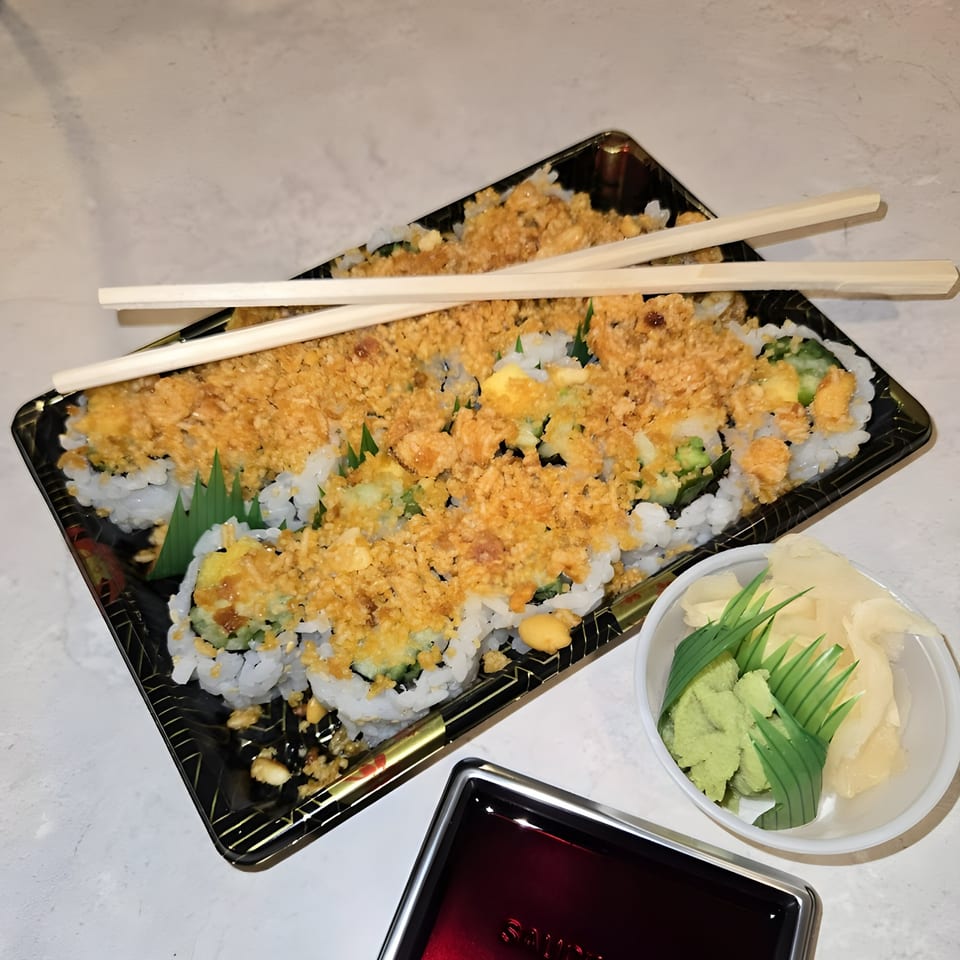 Sushi Guys' crispy sushi rolls with chopsticks, wasabi, ginger, and soy sauce on a white table.